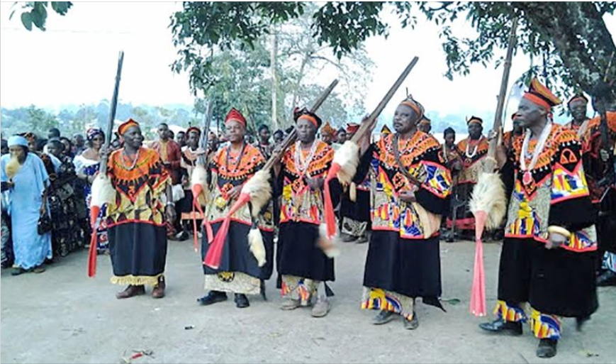 People gathered outdoors in traditional ceremonial regalia