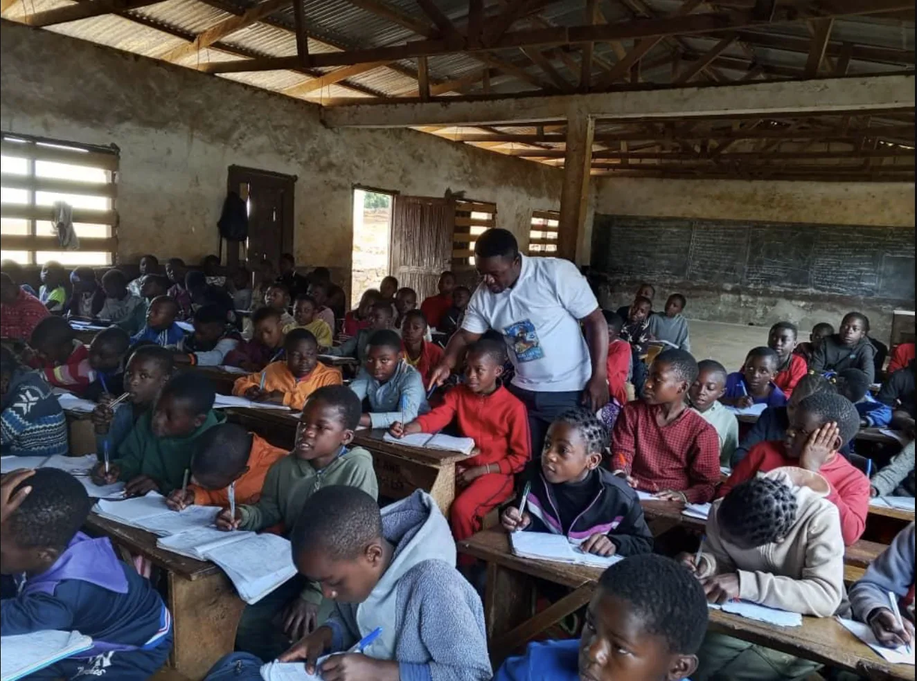 Students at their desks in a classroom, with their teacher