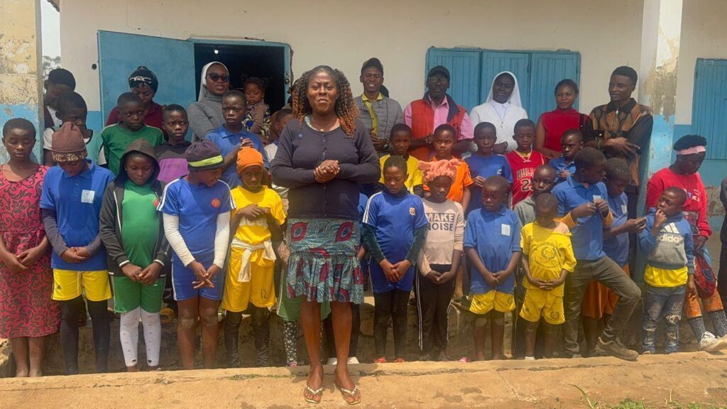 A woman standing in front of a group of schoolchildren and staff outside a school